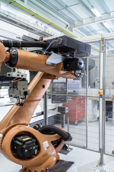 Robotics engineer operating robot aided CNC machine in robotics research facility