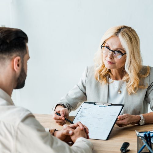 selective-focus-of-recruiter-in-glasses-holding-pen-near-clipboard-and-looking-at-bearded-man.jpg